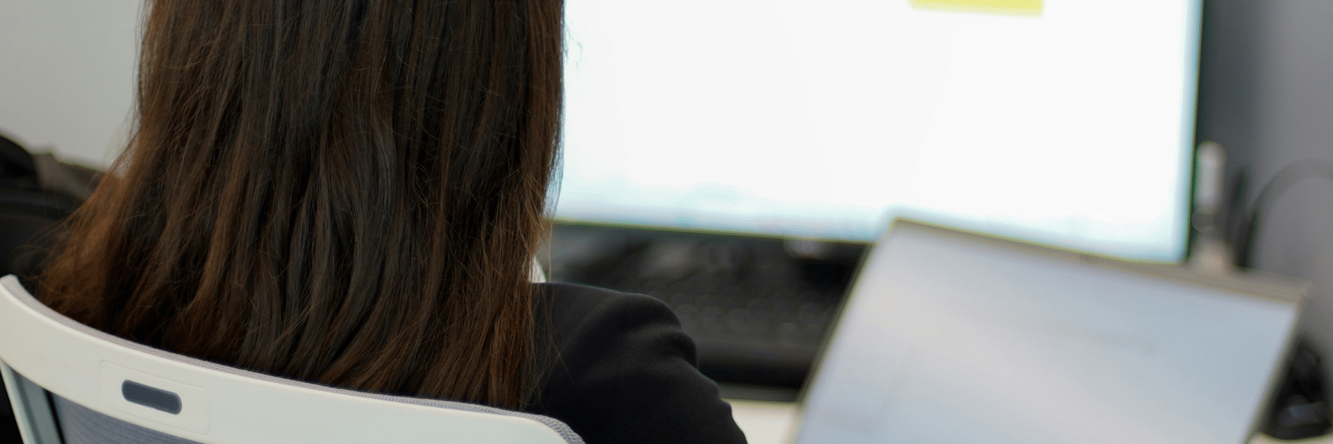 Eine Frau sitzt vor einem Laptop und hat ein Tabellenprogramm geöffnet