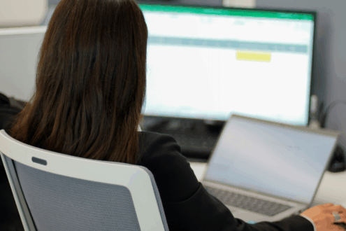 Eine Frau sitzt vor einem Laptop und hat ein Tabellenprogramm geöffnet