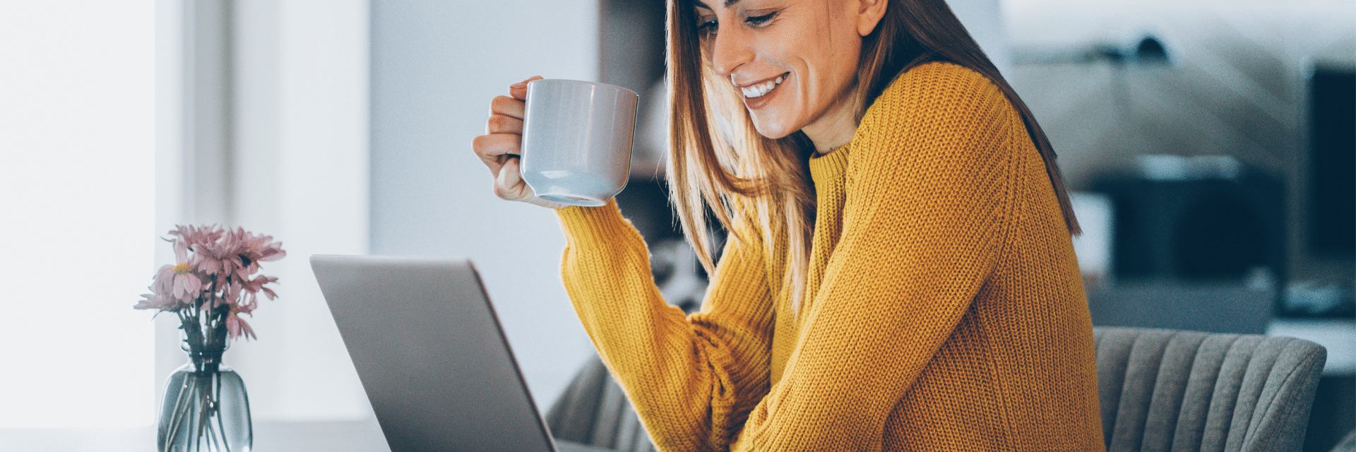 Frau sitzt am Tisch vor einem Laptop